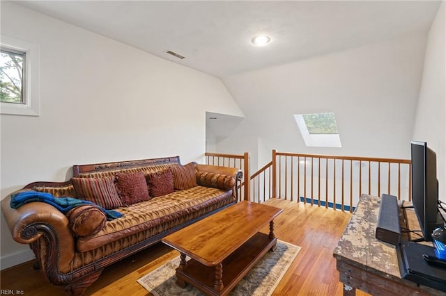 living area with lofted ceiling with skylight, visible vents, and wood finished floors