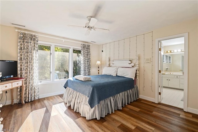 bedroom featuring ensuite bath, baseboards, visible vents, and wood finished floors