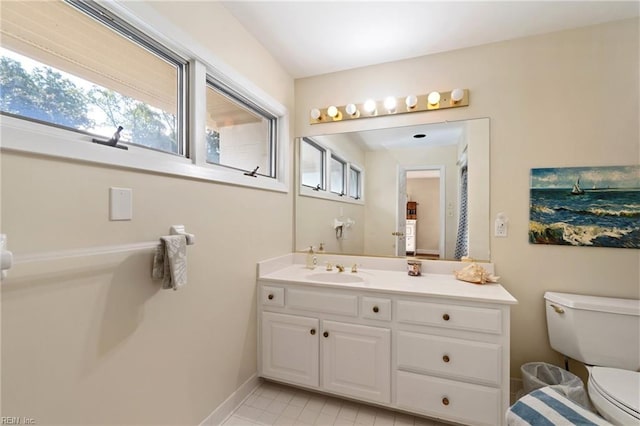 bathroom featuring toilet, baseboards, and vanity