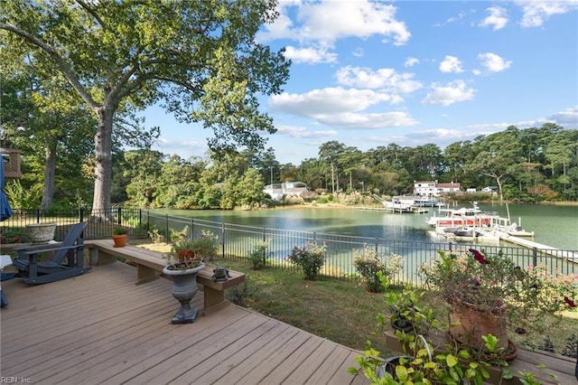 wooden terrace with a water view, fence, and a boat dock