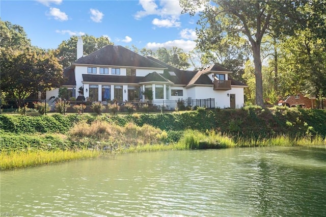 back of house featuring a water view and fence