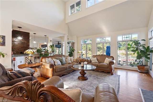 living room with ornate columns, a high ceiling, and wood finished floors