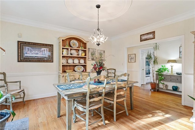 dining room with a chandelier, ornamental molding, baseboards, and light wood-style floors