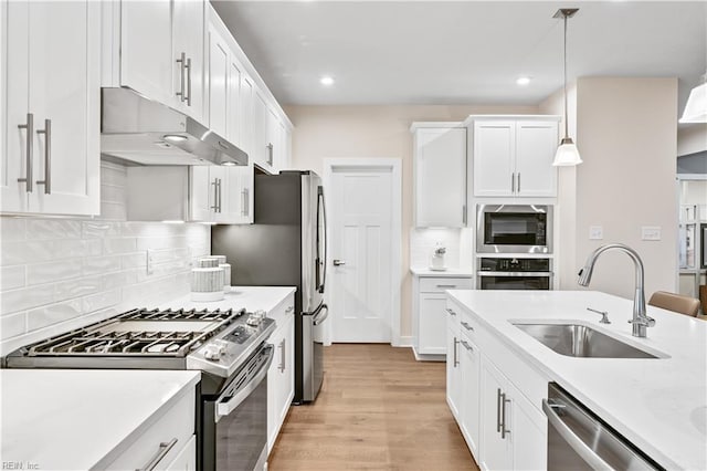 kitchen featuring appliances with stainless steel finishes, a sink, white cabinetry, and under cabinet range hood