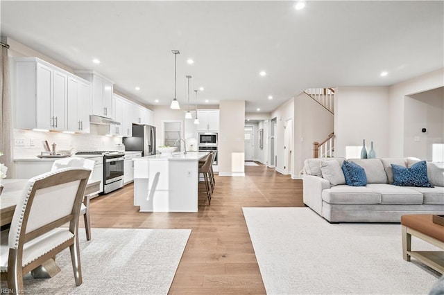 living room featuring light wood-type flooring, stairway, and recessed lighting