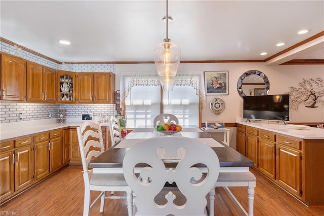 kitchen featuring light wood-style flooring, decorative backsplash, brown cabinetry, and light countertops