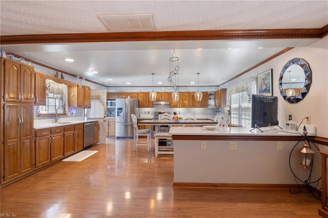 kitchen featuring stainless steel appliances, visible vents, brown cabinetry, a sink, and light wood-type flooring