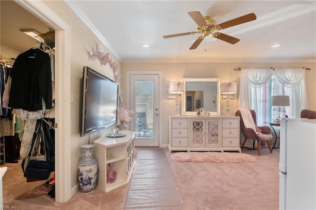 carpeted living area with ornamental molding, a textured ceiling, baseboards, and a ceiling fan