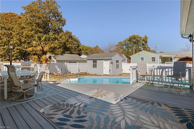 wooden deck with a fenced in pool, a fenced backyard, an outbuilding, a storage unit, and outdoor dining area