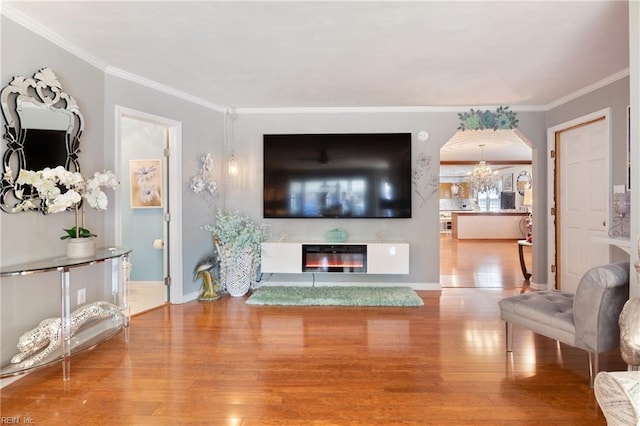 living room with wood-type flooring, arched walkways, and crown molding