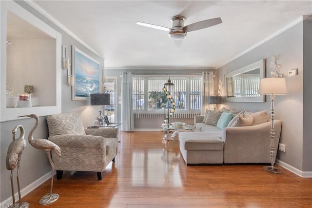 living room featuring ornamental molding, wood finished floors, a ceiling fan, and baseboards