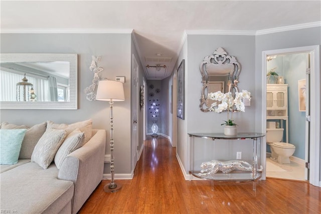 hallway with baseboards, wood finished floors, visible vents, and crown molding