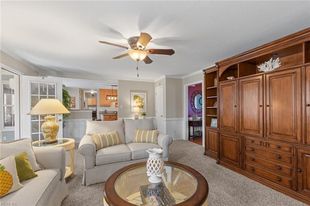 carpeted living room with ornamental molding and a ceiling fan