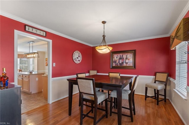 dining space featuring baseboards, light wood-type flooring, and crown molding