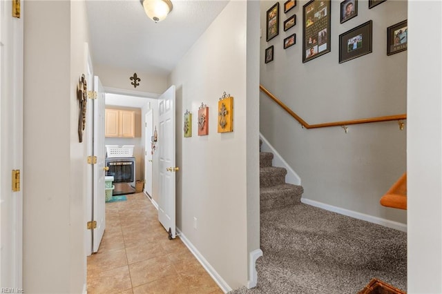 corridor with light tile patterned flooring, baseboards, and stairs