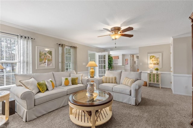 carpeted living room with a textured ceiling, ceiling fan, and ornamental molding