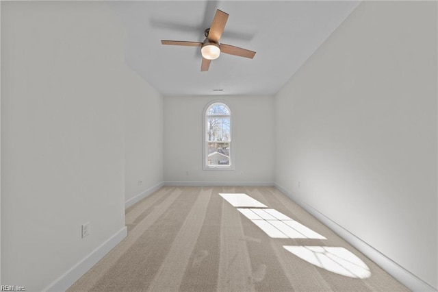 spare room with ceiling fan, baseboards, and light colored carpet