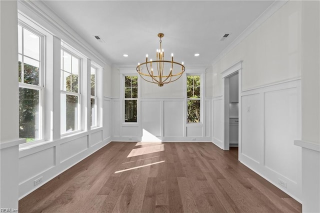 unfurnished dining area with a chandelier, plenty of natural light, visible vents, and a decorative wall