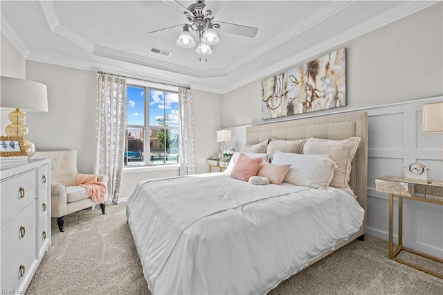 bedroom featuring a raised ceiling, ornamental molding, carpet flooring, and visible vents