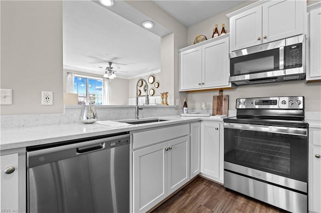 kitchen with appliances with stainless steel finishes, white cabinets, a sink, and ceiling fan