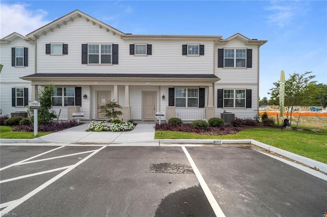 townhome / multi-family property featuring uncovered parking, a front yard, covered porch, and central AC