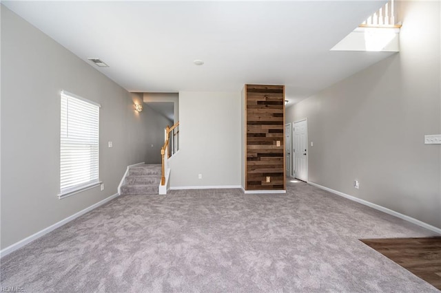 unfurnished living room featuring stairway, carpet, visible vents, and baseboards