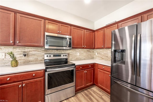 kitchen with stainless steel appliances, tasteful backsplash, light countertops, and light wood-style floors