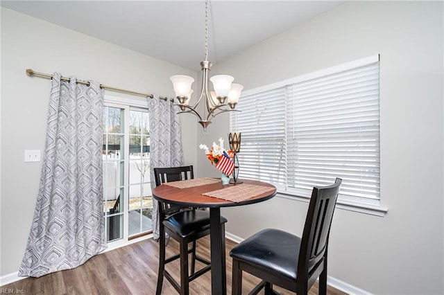 dining space featuring a chandelier, baseboards, and wood finished floors