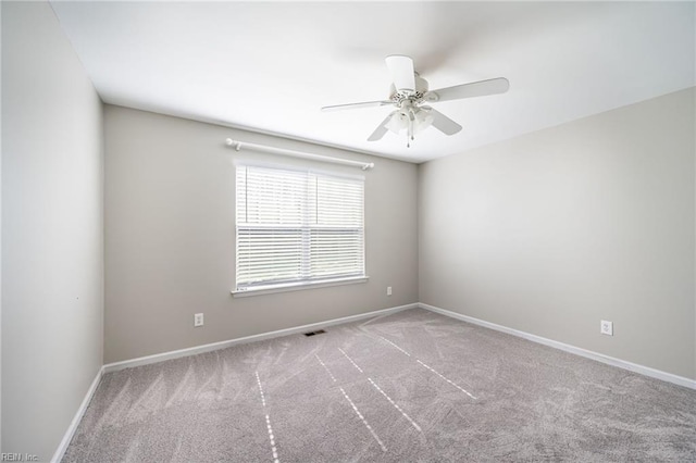 carpeted empty room featuring a ceiling fan, visible vents, and baseboards