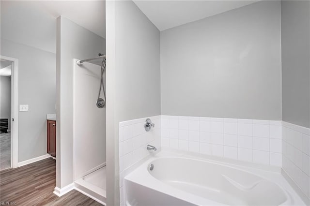 full bath with baseboards, wood finished floors, vanity, a shower stall, and a bath