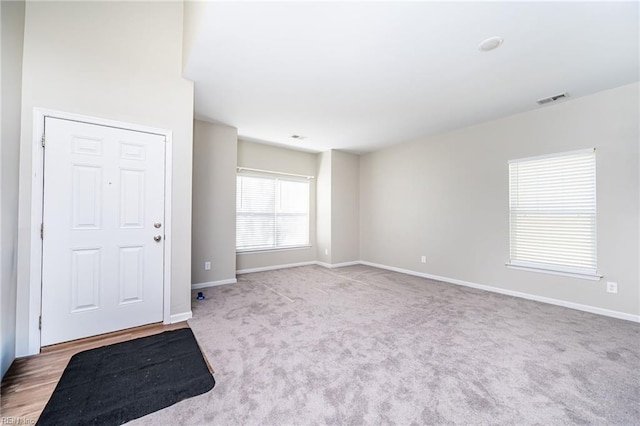 carpeted empty room featuring baseboards and visible vents