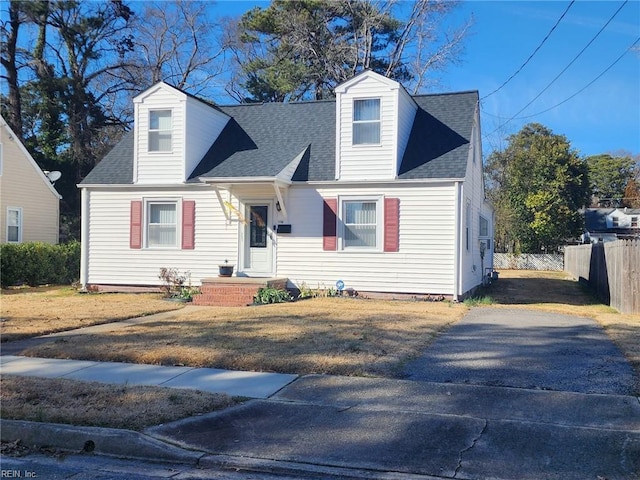 cape cod house with roof with shingles, fence, and driveway