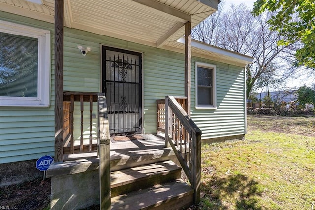 property entrance with a porch and a lawn