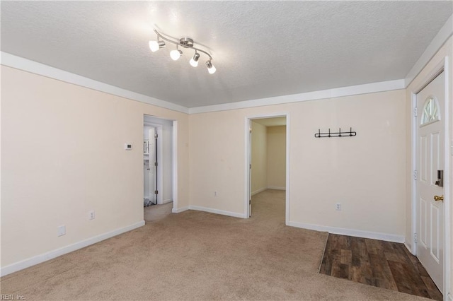 carpeted empty room with a textured ceiling and baseboards