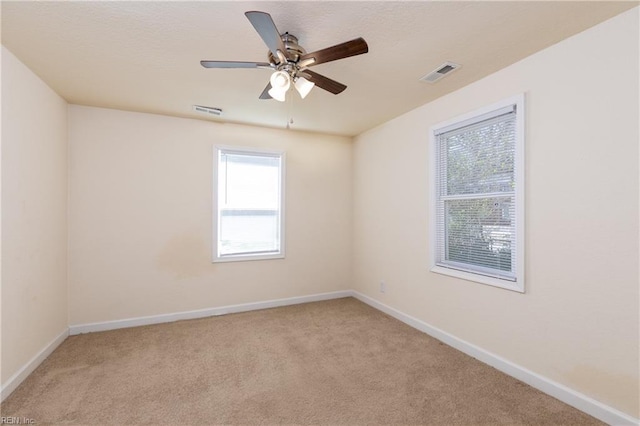 unfurnished room featuring a ceiling fan, carpet, visible vents, and baseboards