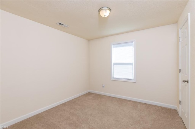 empty room featuring baseboards, visible vents, and light colored carpet