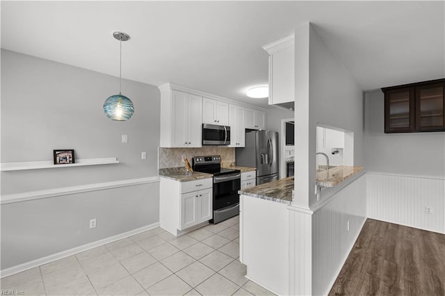 kitchen featuring a wainscoted wall, appliances with stainless steel finishes, light stone counters, and white cabinets