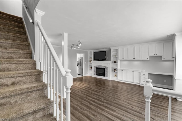 staircase featuring crown molding, a premium fireplace, and wood finished floors