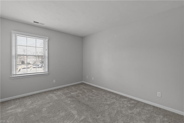 spare room with carpet, visible vents, and baseboards