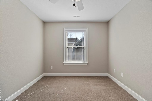 carpeted spare room with ceiling fan, visible vents, and baseboards