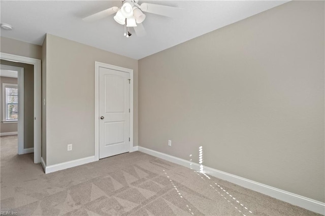 unfurnished bedroom featuring light carpet, baseboards, and a ceiling fan