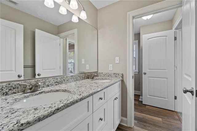 full bath with double vanity, visible vents, a sink, and wood finished floors