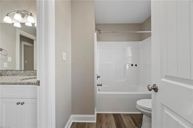 full bath featuring shower / tub combination, toilet, wood finished floors, vanity, and baseboards