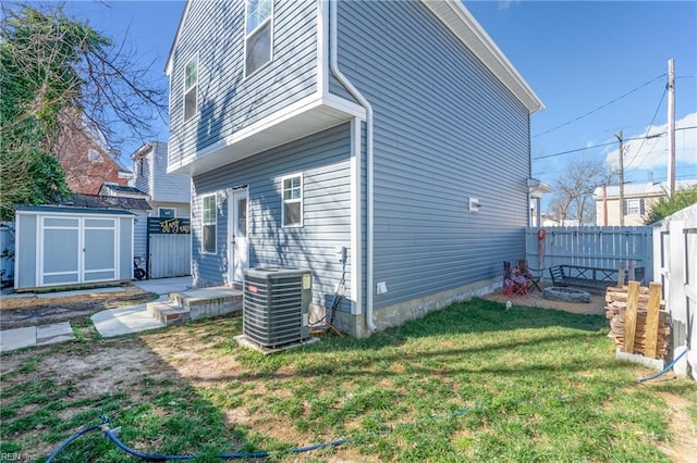 view of home's exterior featuring an outbuilding, a lawn, central AC unit, fence, and a shed