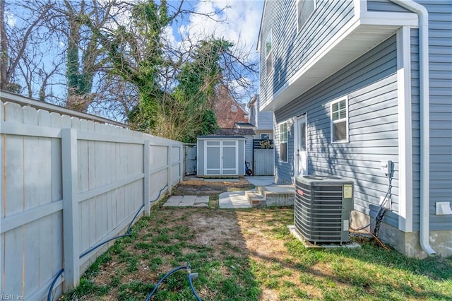 view of yard with a storage shed, central AC, an outbuilding, and a fenced backyard