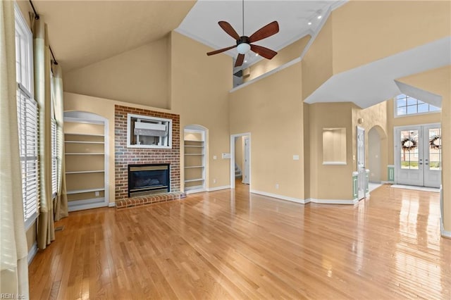 unfurnished living room with built in features, french doors, ceiling fan, wood finished floors, and baseboards