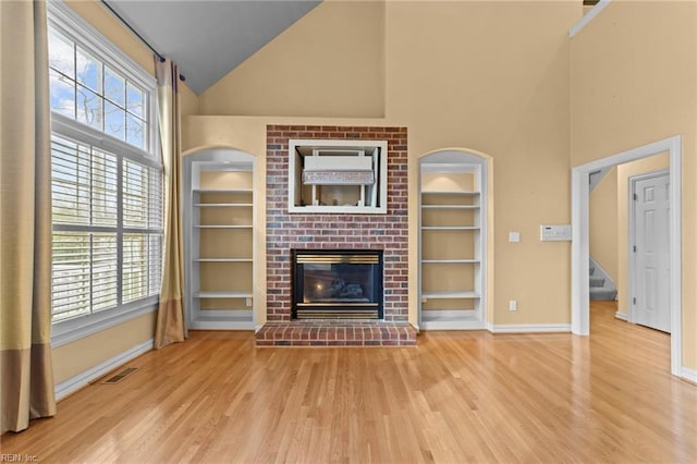 unfurnished living room featuring built in shelves, a wealth of natural light, and visible vents