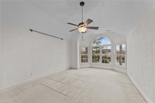 carpeted empty room featuring lofted ceiling, visible vents, a ceiling fan, and baseboards