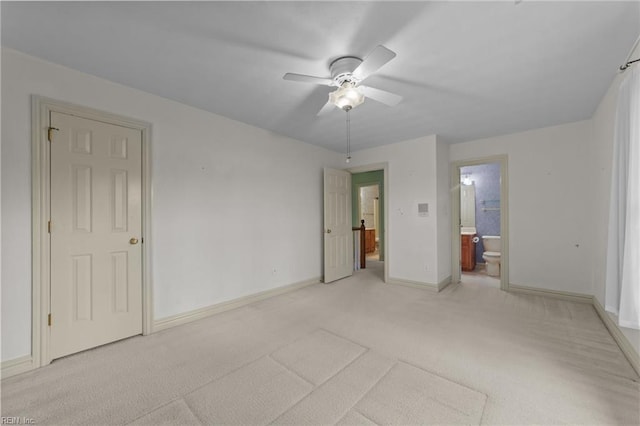 unfurnished bedroom featuring baseboards, light carpet, ceiling fan, and ensuite bath