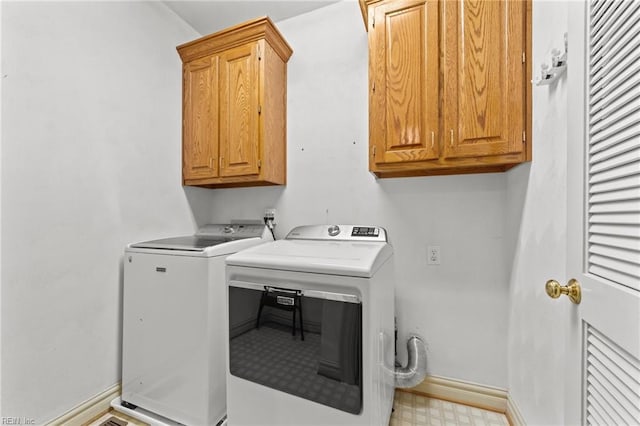 laundry room with cabinet space, baseboards, separate washer and dryer, and light floors